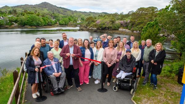 Cllr. Danny Collins accompanied by approximately 25 people as he cuts the ribbon at Blue Pool Trails, Glengarriff.