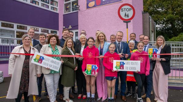 A group of people in front of a school cutting a red ribbon