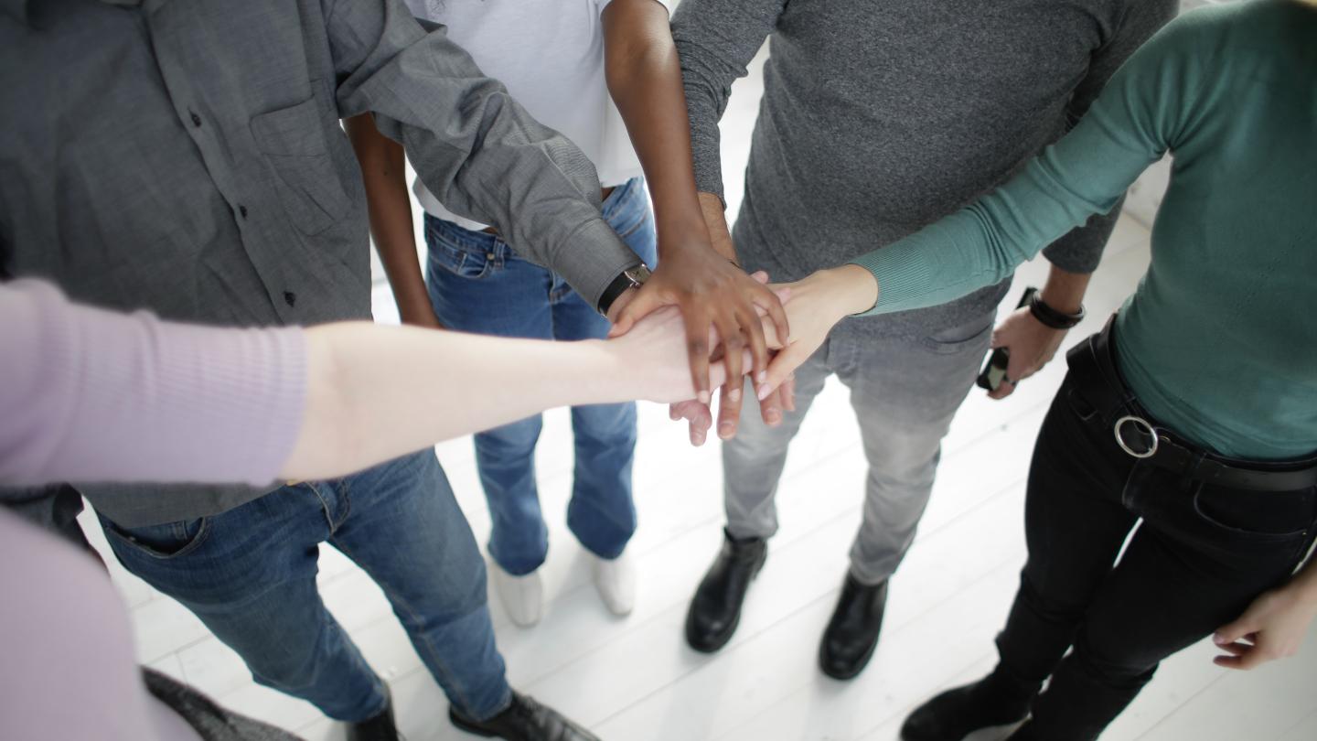 People standing arms outstretched crossing hands