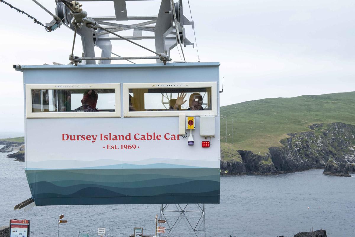 A cable car carrying people across an expanse of water to an Island