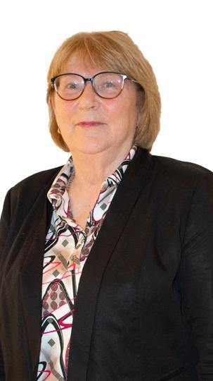 A person wearing glasses, a black blazer, and a patterned shirt against a white background.