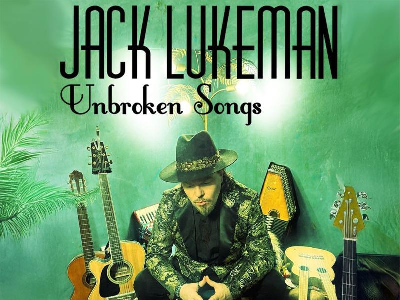 A promotional poster for Jack Lukeman's "Unbroken Songs" with the artist seated among various musical instruments.