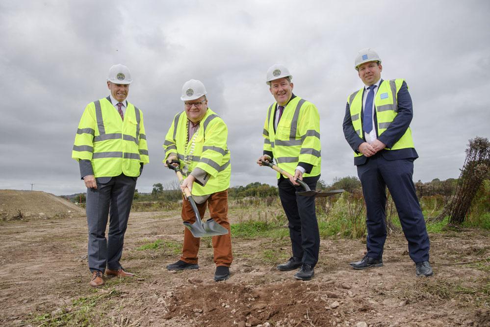 A group of men wearing safety vests and standing on a dirt hill