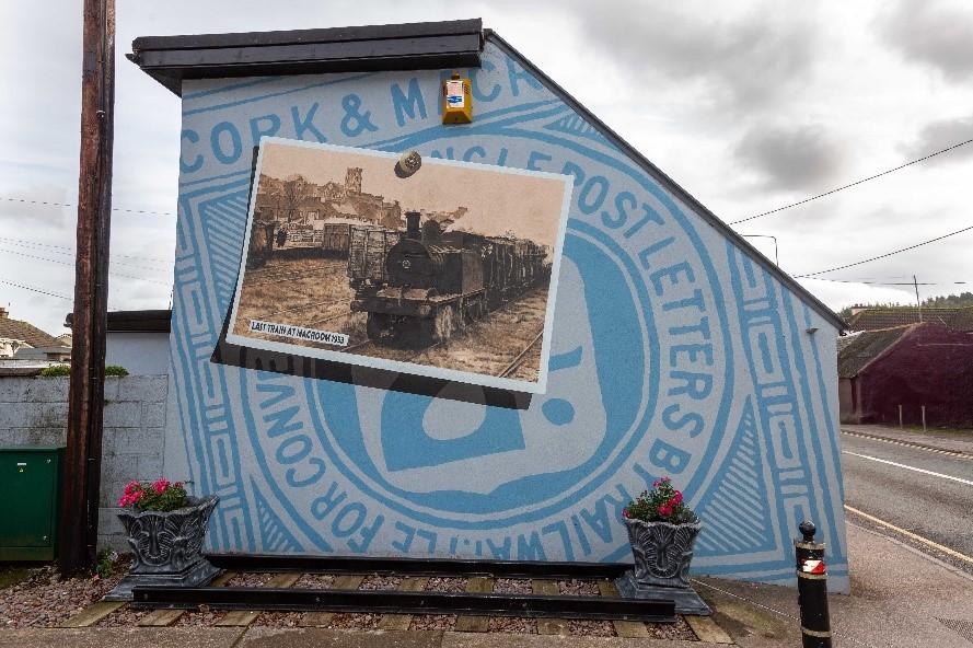 A mural on the gable of a building containing a background logo and an old photograph