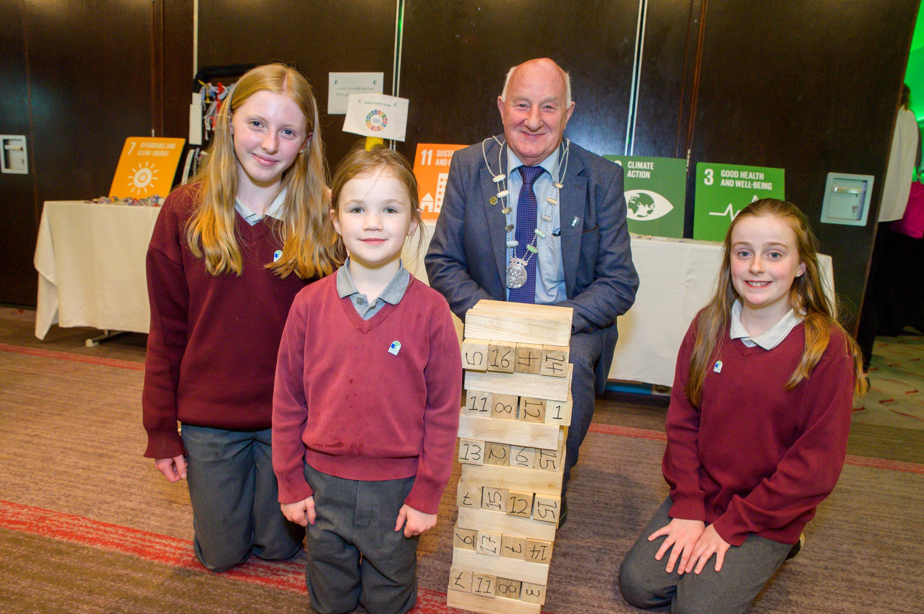 A man and a group of children standing beside jenga blocks