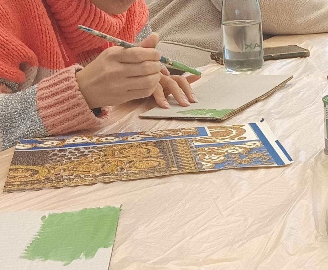 a person drawing with a coloured pencil onto a sheet of paper