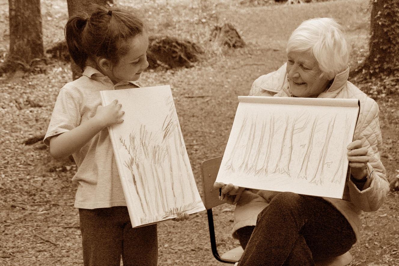 An elderly lady and a female child comparing drawings of trees.