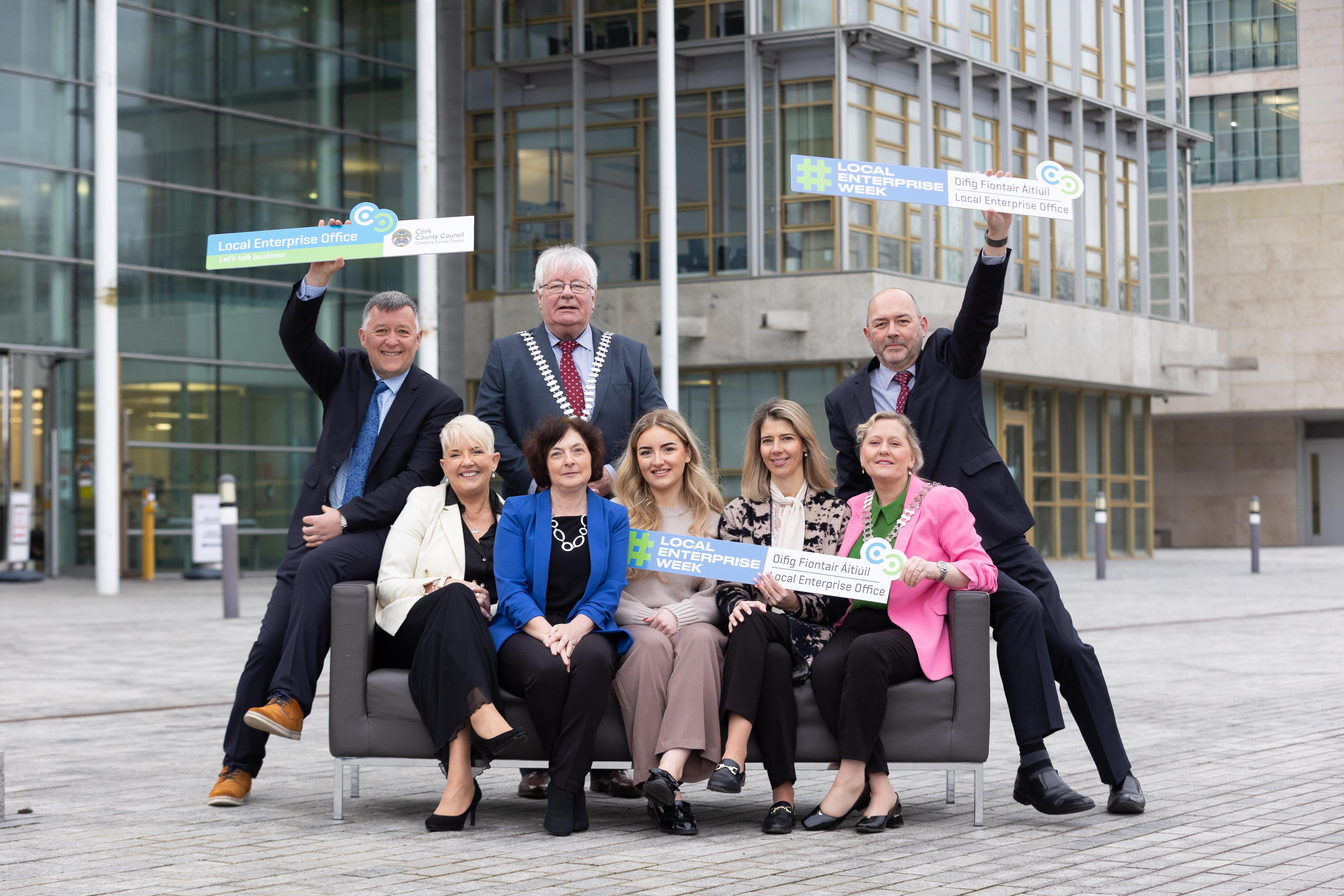 Mayor Joe Carroll and members of LEO's in Cork sitting on couch outside County Hall while holding LEO week signs.