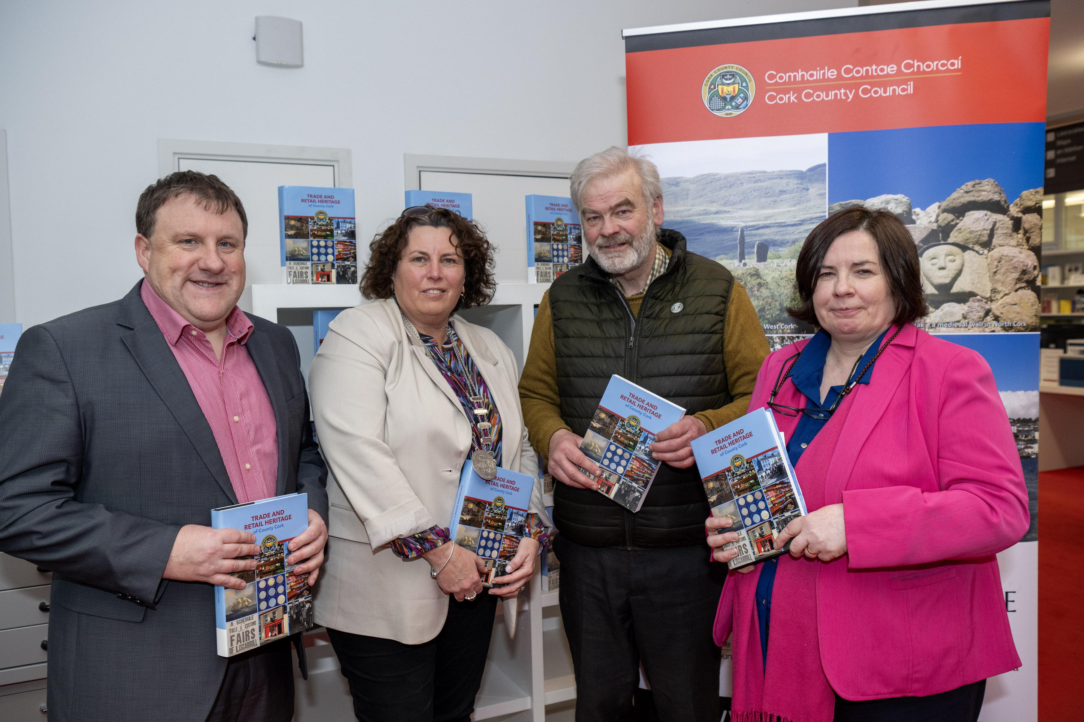 Moira Murrell along with two men and one woman holding Retail Heritage Book